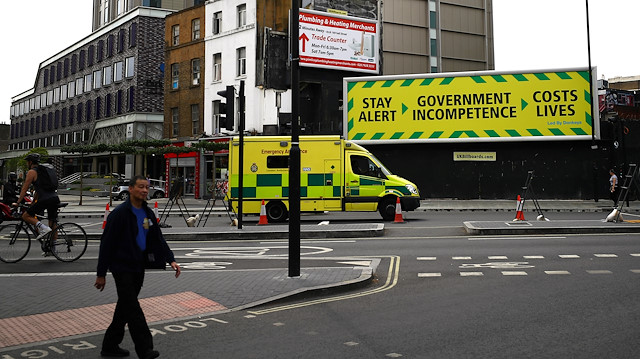 An anti-government poster is seen in London as an ambulance passes