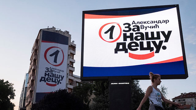  woman walks past election campaign posters of ruling Serbian Progressive Party 