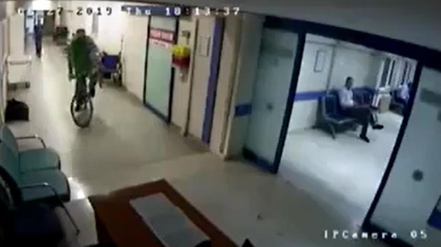Hastane koridorunda bisiklet süren doktor kamerada