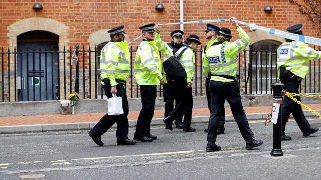 Police officers cross the cordon at the scene of multiple stabbings in Reading, Britain