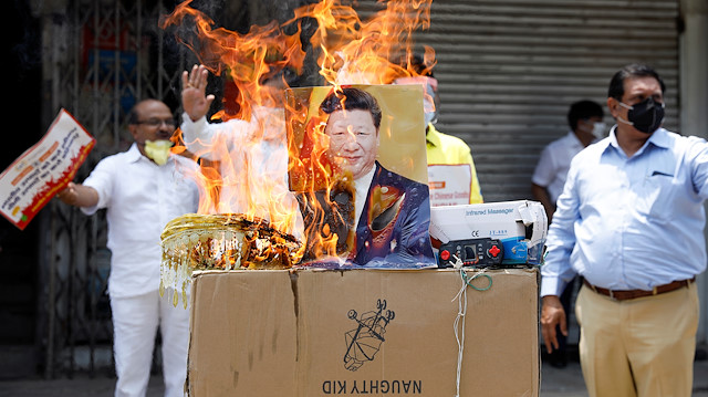 Demonstrators burn products made in China and a defaced poster of Chinese President Xi Jinping