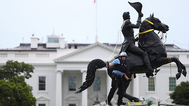 A U.S. Park Police officer removes ropes and chains from a statue 