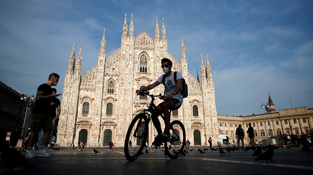FILE PHOTO: A man wearing a protective face mask rides a bicycle at Piazza Duomo, as Italy eases some of the lockdown measures put in place during the coronavirus disease (COVID-19) outbreak, in Milan, Italy May 18, 2020. 