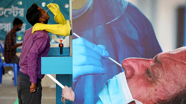 Health worker collects a swab sample from a man at Mugda Medical College and Hospital, as the coronavirus disease (COVID-19) outbreak continues, in Dhaka, Bangladesh, June 23, 2020.