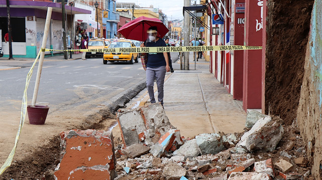 A woman walks by debris from a building damaged during a quake, in Oaxaca, Mexico June 23, 2020.  