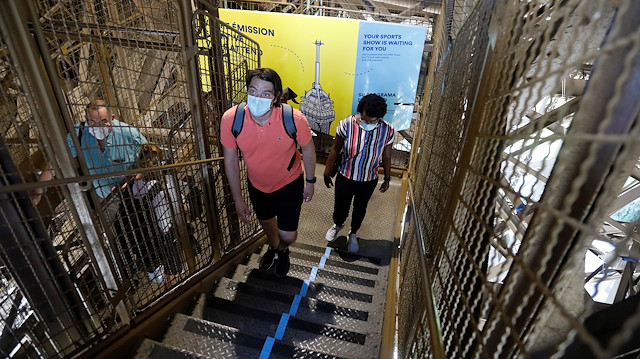 People wearing protective face masks climb the stairs as they visit the Eiffel Tower in Paris on its reopening day to the public following the coronavirus disease (COVID-19) outbreak in France, June 25, 2020