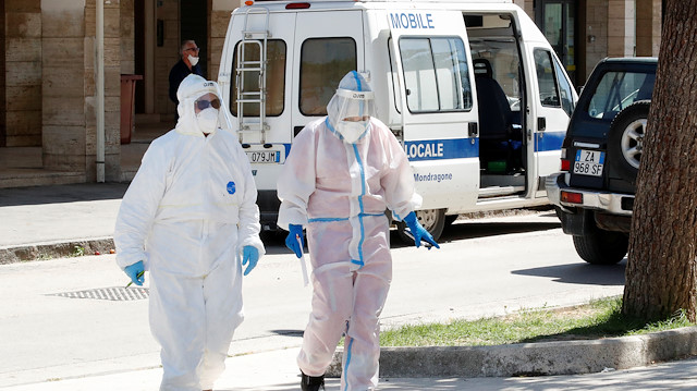Healthcare workers in protective suits are seen near a residential complex, where 49 people tested positive for the coronavirus disease (COVID-19) and that was cordoned off after it was placed under quarantine, in the village of Mondragone, northwest of Naples, Italy, June 26, 2020. 