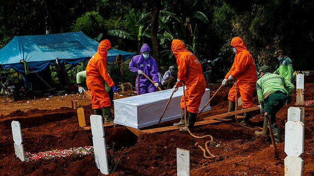 Workers wearing protective suits bury a coffin at the Muslim burial area provided by the government for victims of the coronavirus disease (COVID-19) at Pondok Ranggon cemetery complex in Jakarta, Indonesia, June 27, 2020