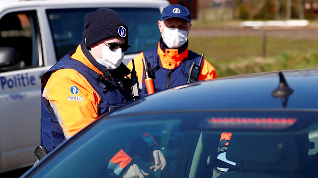FILE PHOTO: Belgian police officers wearing a protective mask control a driver on the Belgian-Dutch border during the coronavirus lockdown imposed by the Belgian government in an attempt to slow down the coronavirus disease (COVID-19), in Meersel-Dreef, Belgium March 25, 2020. 