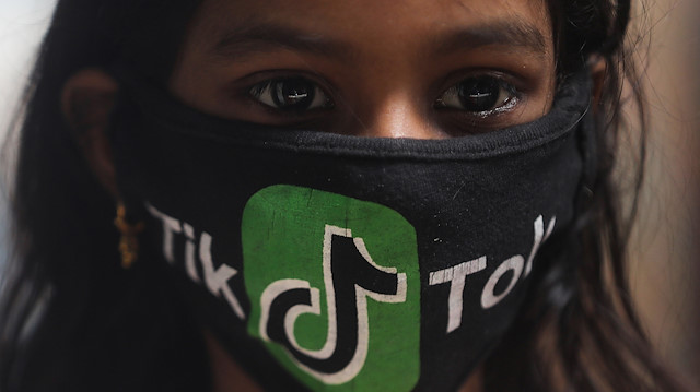 A girl wearing a protective mask depicting the TikTok logo poses for a picture inside a slum in Mumbai, India, July 1, 2020