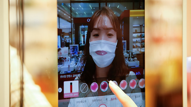 A woman wearing a mask to avoid the spread of the coronavirus disease (COVID-19) shops using AR make up at a cosmetic shop in a department store in Seoul, South Korea, July 2, 2020