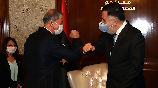 Bakan Akar ve Libya Başbakanı Serrac'ın koronavirüs nedeniyle yaptığı selamlaşma. 