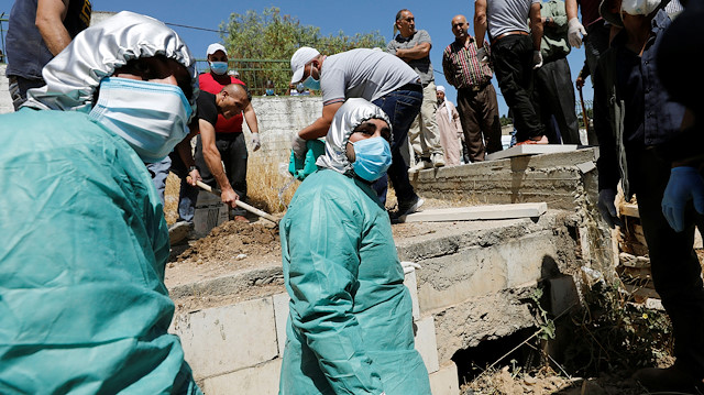 Palestinians bury the body of a woman, who has died after contracting the coronavirus disease (COVID-19), in a cemetery in Hebron in the Israeli-occupied West Bank June 29, 2020. REUTERS/Mussa Qawasma

