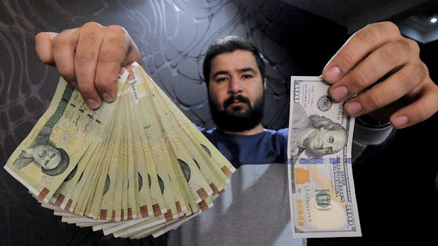 A money changer poses for the camera with a U.S hundred dollar bill