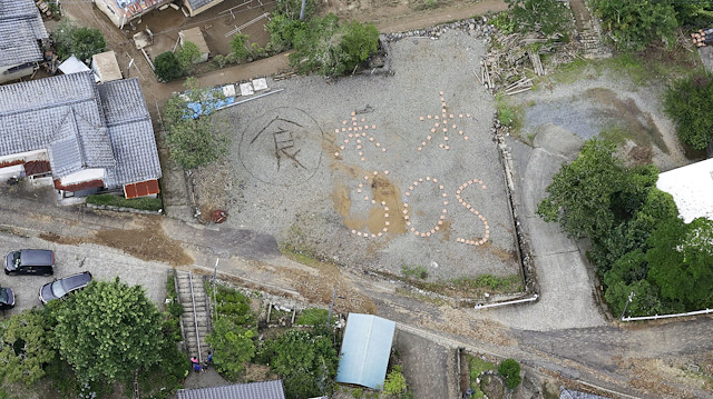 An aerial view shows the words "Rice, Water, SOS" spelled out on the ground 