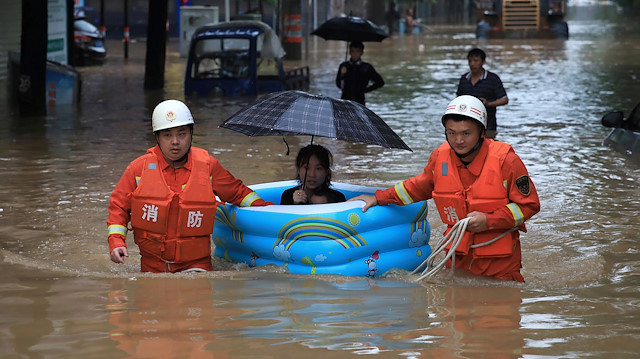 Rescue workers wade through flood waters as they evacuate a woman