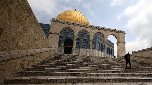 A man walks in front of the Dome of the Rock
