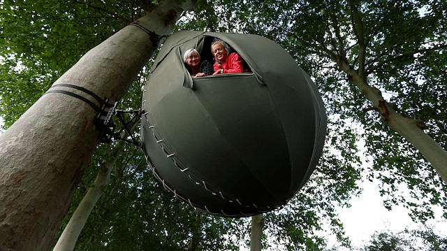 Guests pose a they sit inside a tear drop-shaped tent hanging from a tree created by Dutch artist Dre Wapenaar, offering an unusual accommodation for tourists in the Belgian countryside, near Borgloon, Belgium, July 7, 2020