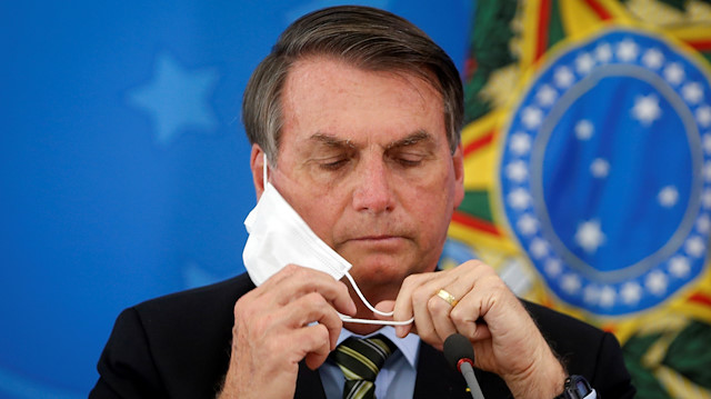 Brazil's President Jair Bolsonaro adjusts his protective face mask 