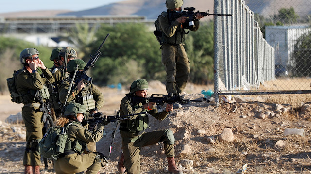 Israeli troops point their weapons at Palestinian demonstrators during a protest against Israel's plan to annex parts of the occupied West Bank, in Jordan Valley June 24, 2020. REUTERS/Mohamad Torokman

