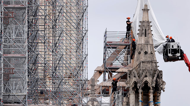 FILE PHOTO: Workers prepare to remove damaged scaffolding elements from the remains of the burnt roof of Notre Dame Cathedral in Paris, France, June 8, 2020. 