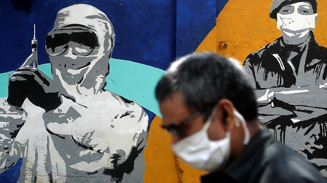 File photo: A man wearing a protective mask walks past a graffiti paying tribute to police and healthcare workers during a lockdown to slow the spread of the coronavirus disease (COVID-19) in Mumbai, India June 24, 2020. 