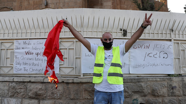 A Palestinian Christian man burns a Turkish flag outside Turkey's consulate in Jerusalem during a protest against Ankara's decision to convert Istanbul's ancient Hagia Sophia from a museum back into a mosque, July 13, 2020.