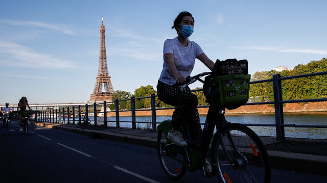 A woman wearing a protective mask rides a Velib bicycle-sharing service near the Eiffel Tower