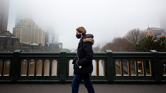 A person in a protective face mask walks along the Princes Bridge amidst a lockdown in response to an outbreak of the coronavirus disease (COVID-19) in Melbourne, Australia, July 17, 2020. AAP Image/Daniel Pockett via Reuters