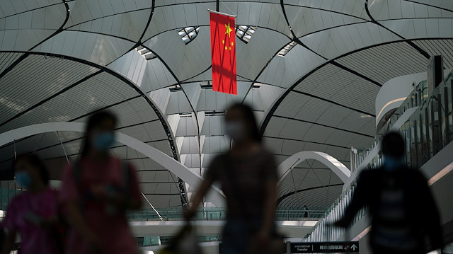 File photo: People wearing face masks following the coronavirus disease (COVID-19) outbreak walk under a Chinese flag at Beijing Daxing International Airport in Beijing, China July 24, 2020. 