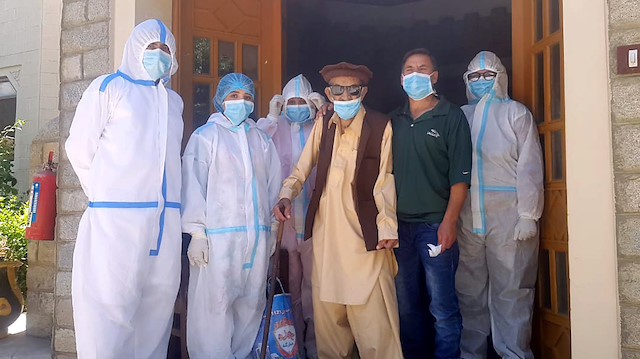Abdul Alim, 103, stands with his son Suhail Aziz and staff members wearing personal protective equipment (PPE) in this group photograph taken after he recovered from coronavirus disease (COVID-19) and was discharged from the Aga Khan Health Services Emergency Response Centre in Booni, Chitral, Pakistan in this undated photograph provided to Reuters