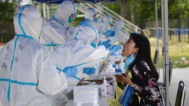 A medical worker in a protective suit conducts a nucleic acid test for a resident, following a new outbreak of the coronavirus disease (COVID-19) in Beijing, China June 20, 2020