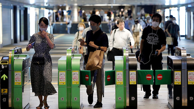 FILE PHOTO: Passengers wearing protective face masks pass through the automated entranceway at a station amid the coronavirus disease (COVID-19) outbreak in Tokyo, Japan July 23, 2020