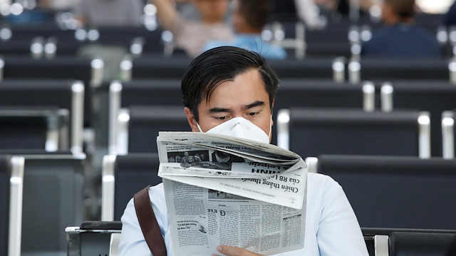 A man wearing a protective mask reads newspaper, following an outbreak of the novel coronavirus, at the Da Nang airport in Danang city, Vietnam February 23, 2020. 