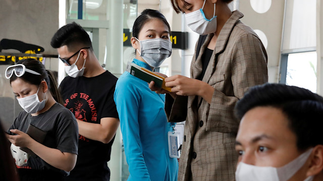A ground staff member of Vietnam Airlines and passengers wearing protective mask, following an outbreak of the novel coronavirus, wait for boarding at the Danang airport in Danang city, Vietnam February 23, 2020. REUTERS/Kham

