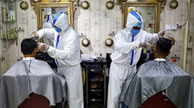 Barbers wearing protective suits and face masks provide hair cut service to the customers inside a salon amid the coronavirus disease (COVID-19) outbreak, in Dhaka, Bangladesh June 16, 2020. REUTERS/Mohammad Ponir Hossain TPX IMAGES OF THE DAY

