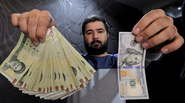 FILE PHOTO: A money changer poses for the camera with a U.S hundred dollar bill (R) and the amount being given when converting it into Iranian rials (L), at a currency exchange shop in Tehran's business district, Iran, January 20, 2016. REUTERS/Raheb Homavandi/TIMA