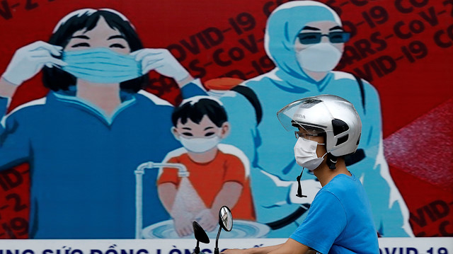 A man wears a protective mask as he drives past a banner promoting prevention against the coronavirus disease (COVID-19) in Hanoi, Vietnam July 31, 2020. 