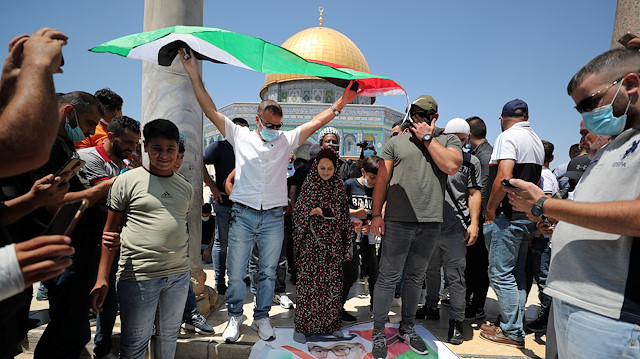 A man holds a Palestinian flag while others stand on an anti-Abu Dhabi Crown Prince Mohammed bin Zayed al-Nahyan poster during a protest against the United Arab Emirates, in front of the Dome of the Rock, in Jerusalem's Old City, August 14, 2020.