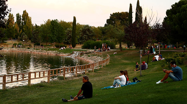 People wearing protective face masks sit at the Las Cruces park during the sunset amid the coronavirus disease (COVID-19) outbreak in Madrid, Spain July 28, 2020.