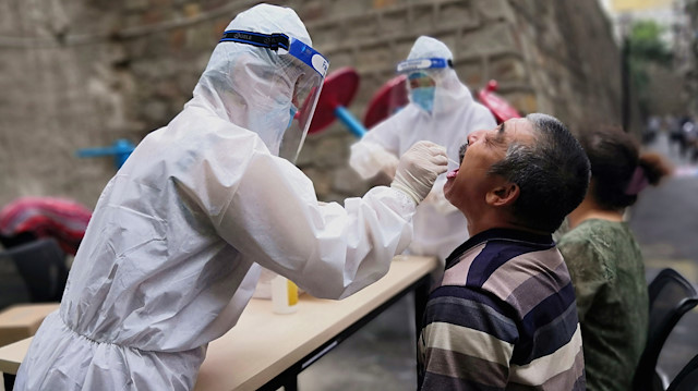 A medical worker in protective suit collects a swab from a man to conduct free nucleic acid tests for residents in the residential compound, after new cases of coronavirus disease (COVID-19) were found in Urumqi, Xinjiang province, China July 19, 2020