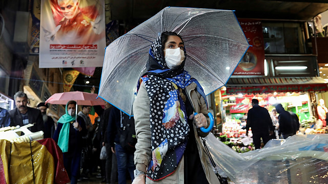 An Iranian woman wears a protective face mask and gloves