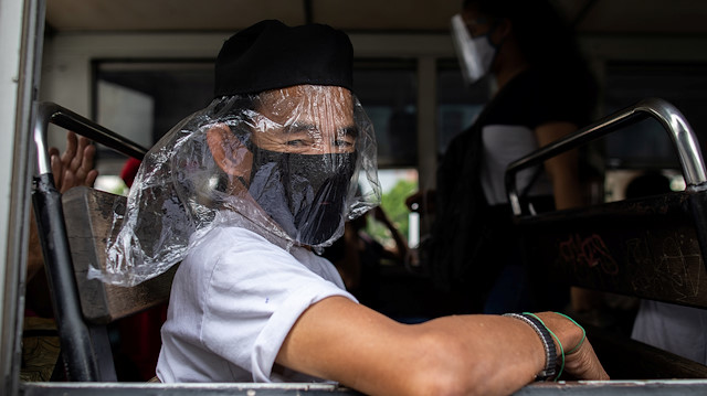 A passenger on board a bus wears a face mask and a makeshift face shield, both mandatory in public transportation, to help curb coronavirus disease (COVID-19) infections, in Quezon City, Metro Manila, Philippines, August 19, 2020