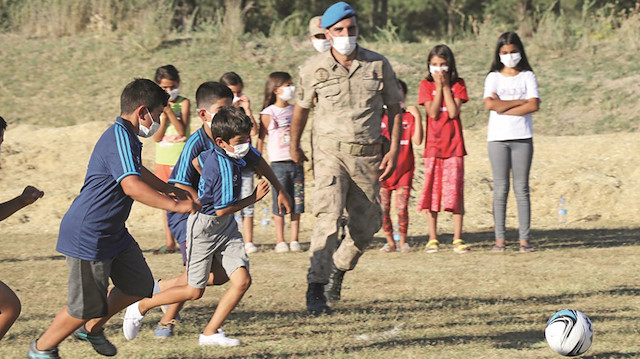 Köyün girişinde futbol oynayan çocuklar asker ağabeylerinden forma, spor ayakkabı ve futbol topu istedi.