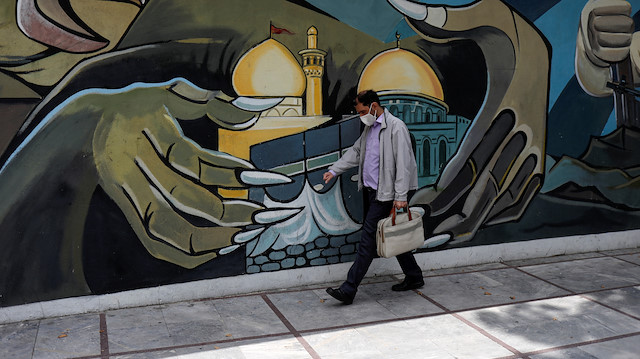 A man wearing a protective face mask walks past a Palestine mural on the wall following the outbreak of the coronavirus disease (COVID-19), in Tehran, Iran, April 30, 2020. WANA (West Asia News Agency)/Ali Khara via REUTERS