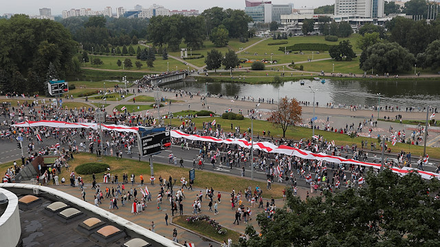 People carry a large historical white-red-white flag of Belarus 