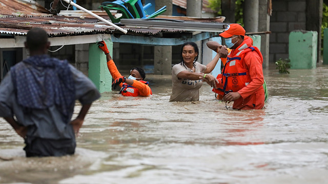 Members of the Civil Defence help a woman in a flooded street after the passage of Storm Laura, in Azua, Dominican Republic August 23, 2020