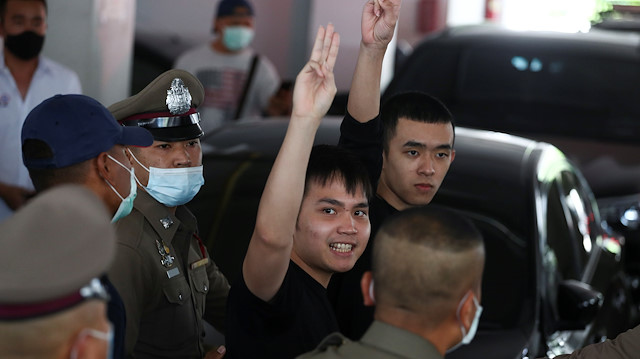Pro-democracy leaders Tattep Ruangprapaikitseree and Panumas Singprom, flash the three-fingers salute as they are escorted out of a police station to be taken to the criminal court after being arrested, in Bangkok, Thailand, August 26, 2020.