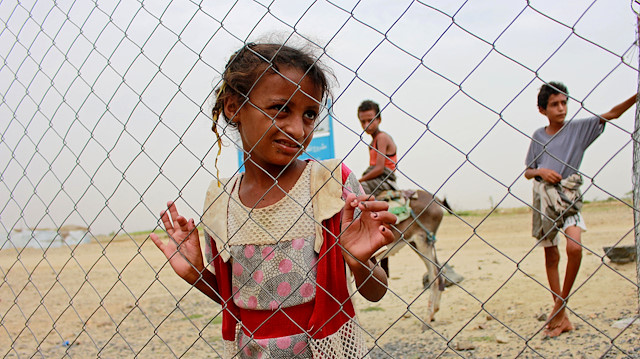 A girl looks through the fence of a closed clinic at a camp for internally displaced people near Abs of Hajjah province, Yemen August 19, 2020