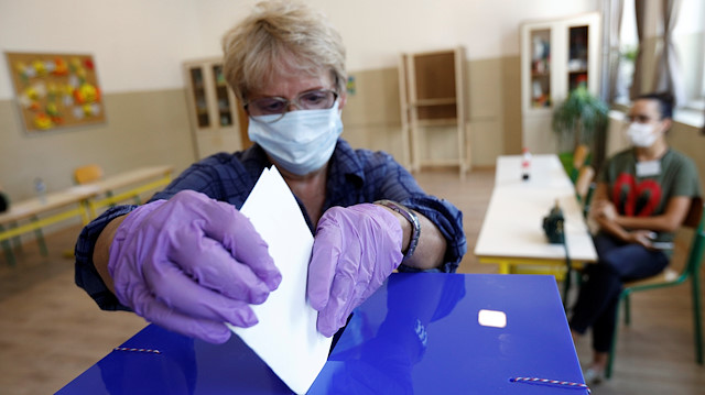 A woman wearing a face mask and gloves due to the ongoing coronavirus disease (COVID-19) outbreak casts her vote at a polling station during the general election in Podgorica, Montenegro August 30, 2020.